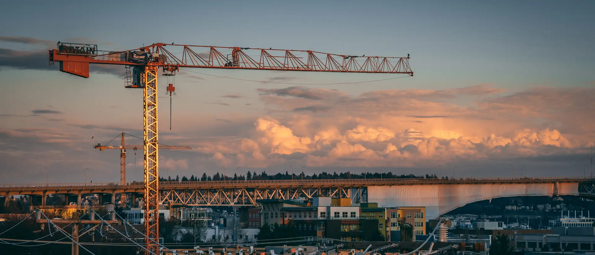 Tower crane over an active Aeterna Group construction site at dusk